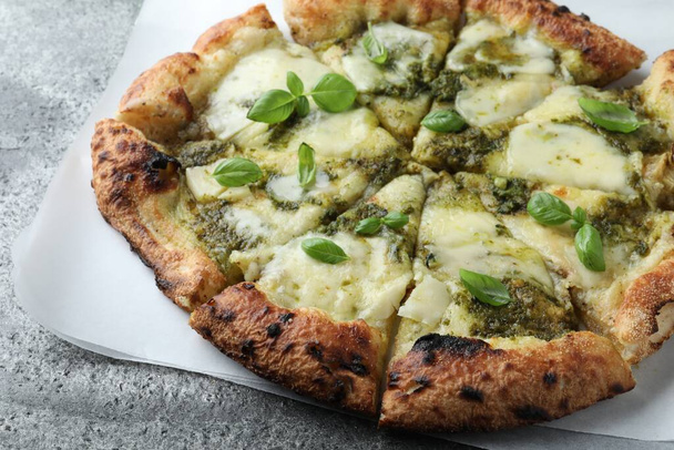 Delicious pizza with pesto, cheese and basil on grey table, closeup - Foto, imagen
