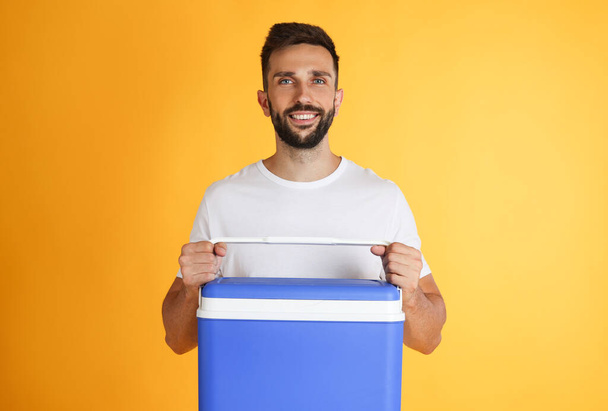 Happy man with cool box on yellow background - Photo, image