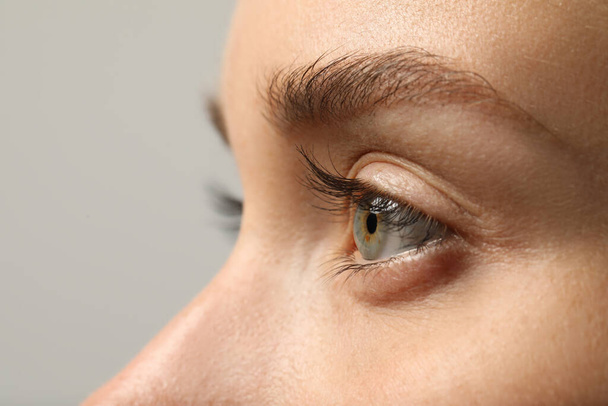 Beautiful woman with grey eye on color background, closeup - Фото, зображення