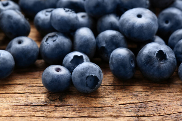 Many tasty fresh blueberries on wooden table, closeup - Foto, Imagen