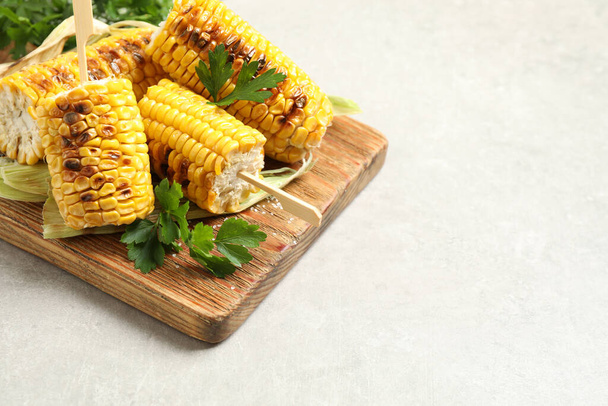 Tasty grilled corn cobs on light table. Space for text - Photo, image