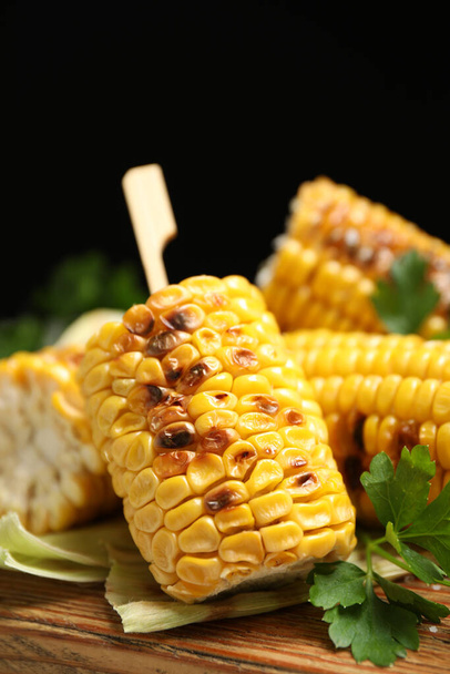 Tasty grilled corn cobs on wooden board, closeup - Фото, изображение