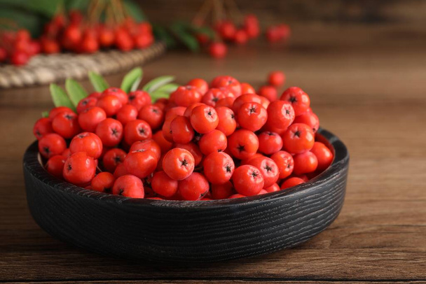Plate with fresh ripe rowan berries on wooden table, closeup - Fotó, kép