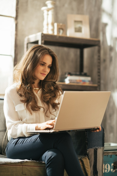 Młoda kobieta za pomocą laptopa siedząc w loft Apartament - Zdjęcie, obraz
