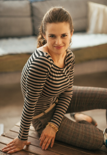 Portrait of happy young woman sitting in loft apartment - Foto, imagen