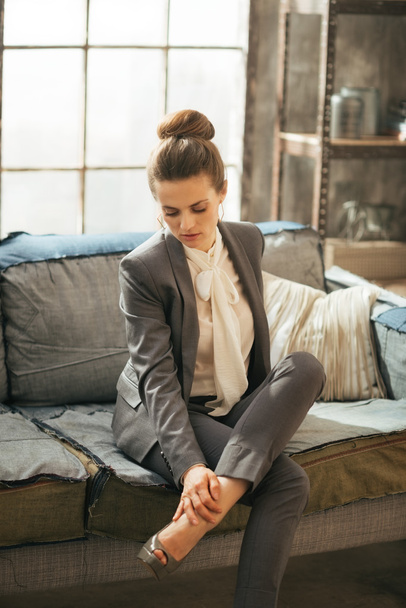 Thoughtful business woman in loft apartment checking tired legs - Photo, Image