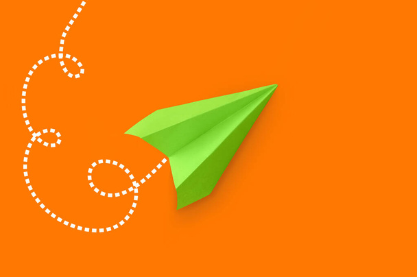 Green paper plane on orange background - Fotografie, Obrázek