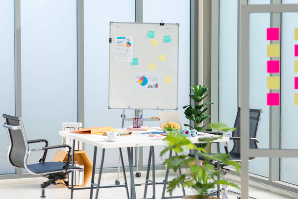 Nobody in empty modern interior architecture design company office meeting room full of stationary corporate equipment, whiteboard with sticky notes and graph chart document, working table and chairs. - Fotoğraf, Görsel