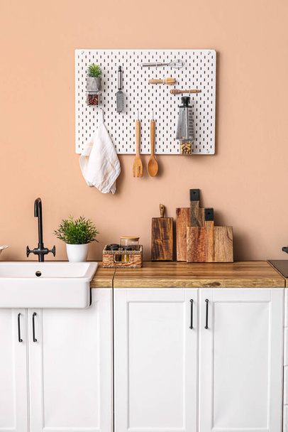 Кухонні лічильники з раковиною і посудом біля бежевої стіни
 - Фото, зображення