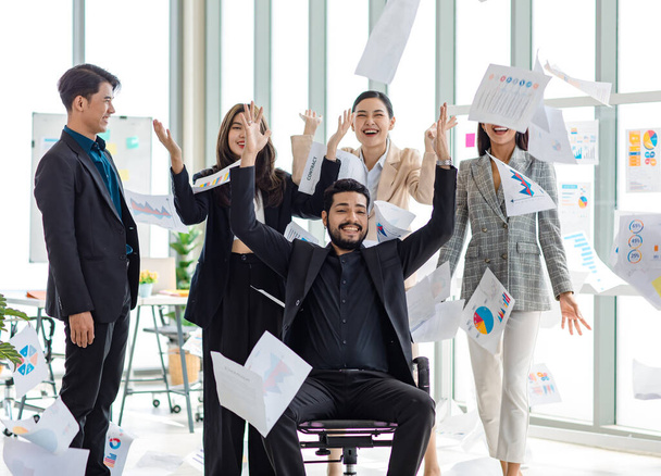 Millennial Asian Indian male female businessman businesswoman group in multinational multicultural company throwing paperwork documents in air celebrating job achievement deal done together in office. - Fotó, kép