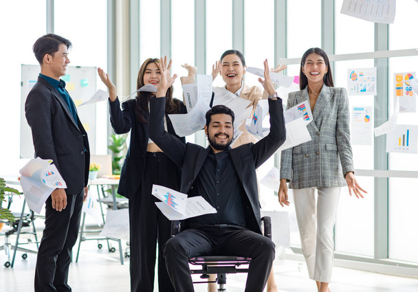 Millennial Asian Indian male female businessman businesswoman group in multinational multicultural company throwing paperwork documents in air celebrating job achievement deal done together in office. - Fotó, kép