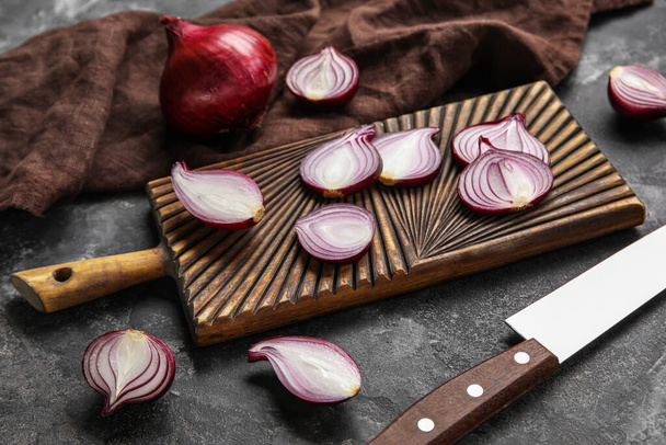 Wooden board with cut red onion on dark background - Foto, afbeelding