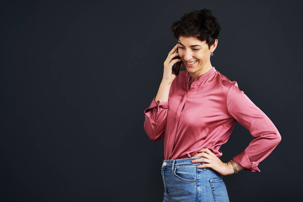 Здравствуйте, чем могу помочь. привлекательная молодая деловая женщина, стоящая и разговаривающая по мобильному телефону на черном фоне в студии - Фото, изображение