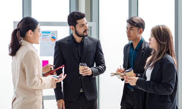 Group of millennial Asian Indian male female businessman businesswoman in formal suit standing holding tablet computer discussing sharing business ideas in multinational company office meeting room. - Photo, image