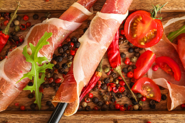 Wooden board with delicious jamon and peppercorns, closeup - Фото, изображение