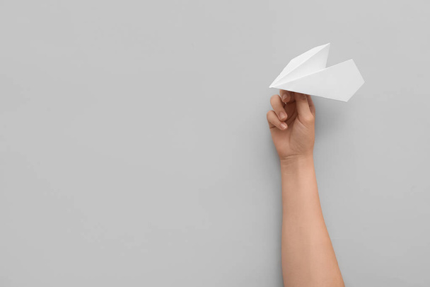 Woman with white paper plane on light background - Foto, Imagen