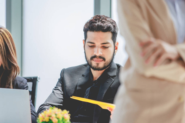 Closeup shot of millennial Asian professional cheerful male businessman in formal suit sitting holding tablet computer busy working with colleague in company conference meeting room. - Foto, Imagem