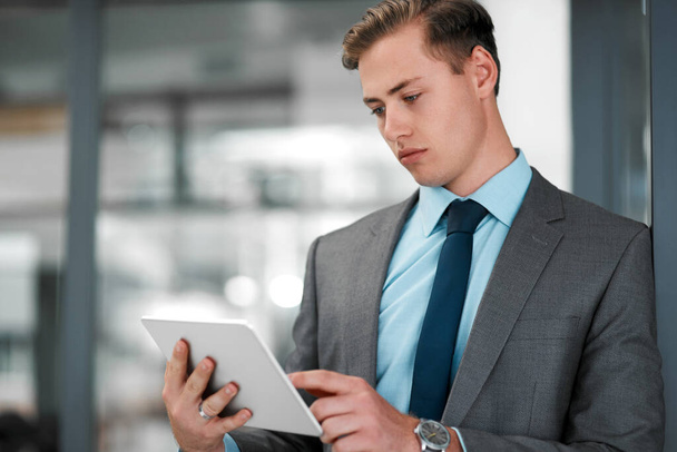 I am destined for success. a handsome young businessman standing alone in his office and using a tablet - Foto, Bild