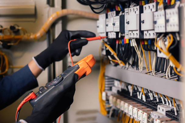 Electrician engineer work tester measuring voltage and current of power electric line in electical cabinet control.and wires on relay protection system. Bay control unit. Medium voltage switchgear. - Photo, Image