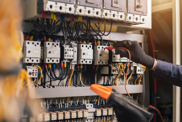 Electrician engineer work tester measuring voltage and current of power electric line in electical cabinet control.and wires on relay protection system. Bay control unit. Medium voltage switchgear. - Foto, Bild