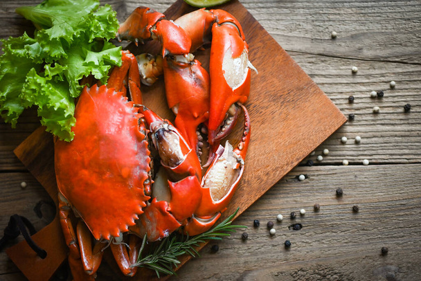 Fresh crab on wooden plate, boiled or steamed crab red in the restaurant, claw crab cooking food seafood plate with chili herbs spices salad - Foto, Bild