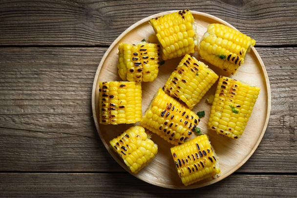 corn food , sweet corn cooked on wooden plate background, ripe corn cobs grilled sweetcorn for food vegan dinner or snack - top view - Foto, imagen