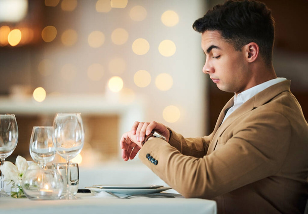 Am I being stood up. a handsome young man checking his watch while sitting in a fancy restaurant - Foto, Imagem