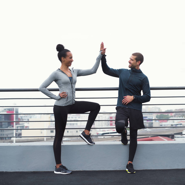 The benefits of exercise linger long after. a sporty young man and woman giving each other a high five while exercising outdoors - Photo, image