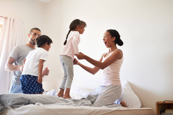 Семья всегда на первом месте. красивая молодая семья из четырех человек веселится и проводит время вместе в своей спальне дома - Фото, изображение