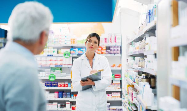 What symptoms do you have. a pharmacist assisting a customer in a chemist - Foto, imagen