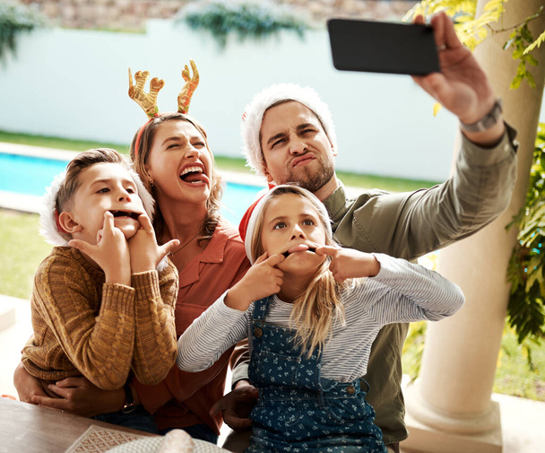 Ας μοιραστούμε αυτή την ειδική περίσταση με τους αγαπημένους μας. μια τετραμελής οικογένεια που βγάζει selfie μαζί την ημέρα των Χριστουγέννων - Φωτογραφία, εικόνα