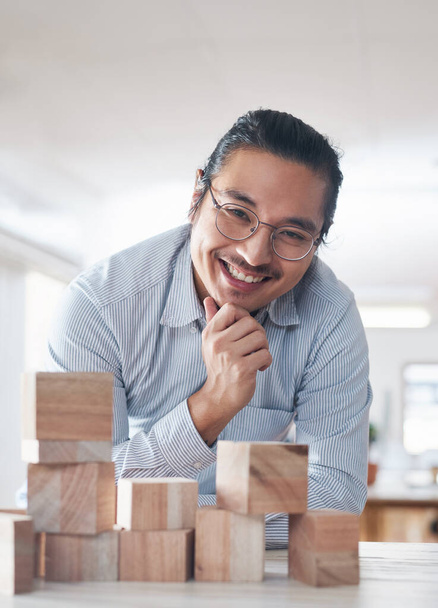 Be open to brand new ideas. a young businessman working with wooden building blocks in a modern office - Photo, image