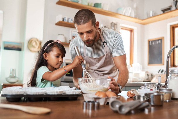 Το αγαπημένο της πράγμα είναι να ψήνει. Ένας νεαρός που μαγειρεύει στο σπίτι με τη μικρή του κόρη. - Φωτογραφία, εικόνα
