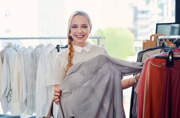 Шоппинг мое любимое занятие. молодая женщина покупает одежду в магазине - Фото, изображение