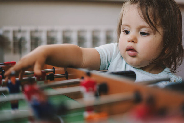 Baby girl is curious about how to play table football. Having fun and recreation of alpha generation kids concept - 写真・画像