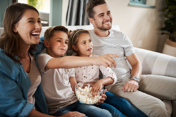 Сімейний час перед усім іншим. щаслива молода сім'я розслабляється на дивані і дивиться телевізор разом вдома
 - Фото, зображення