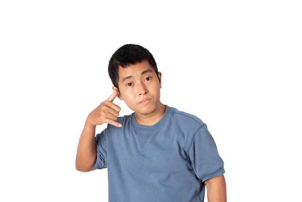 Portrait of young single man wearing t-shirt making call me gesture, sign with hand shaped like phone isolated on white background. Positive human emotions, face expressions. - Photo, Image