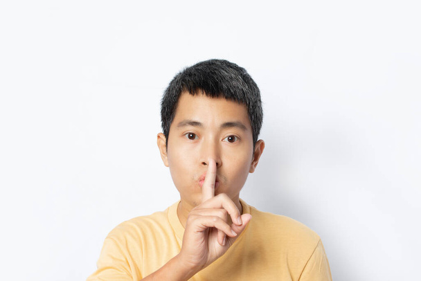 Young man making hush gesture and keep conspiracy isolated on white background. Silence and secret concept. copy space - Photo, Image