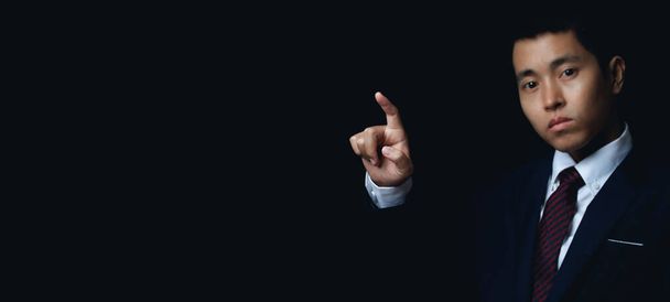 Businessman pointing to something or touching a touch screen on black background. copy space. - Fotó, kép