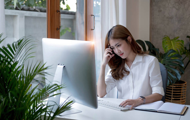 Чарівна азіатська бізнес-леді сидить на ноутбуці в офісі
 - Фото, зображення