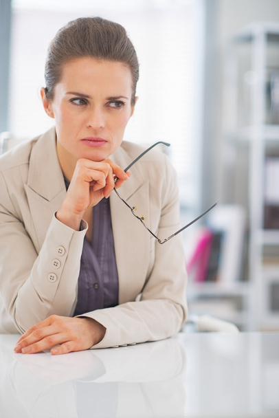 Thoughtful business woman with eyeglasses in office - Foto, imagen