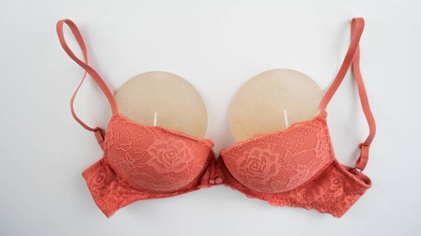 Breast implants in an orange bra on a white background - Fotoğraf, Görsel