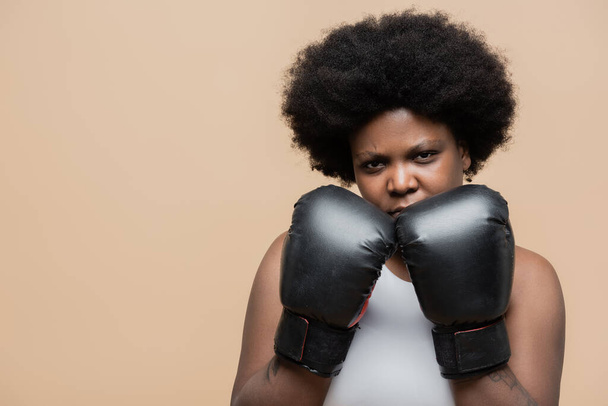 curly african american plus size woman in leather boxing gloves isolated on beige - Foto, Imagen