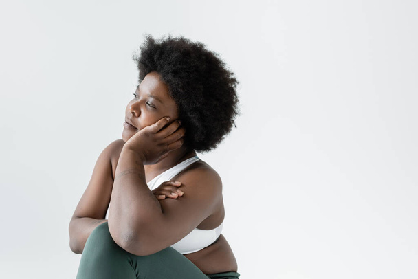 thoughtful african american plus size woman in sportswear looking away isolated on grey - Foto, Imagem