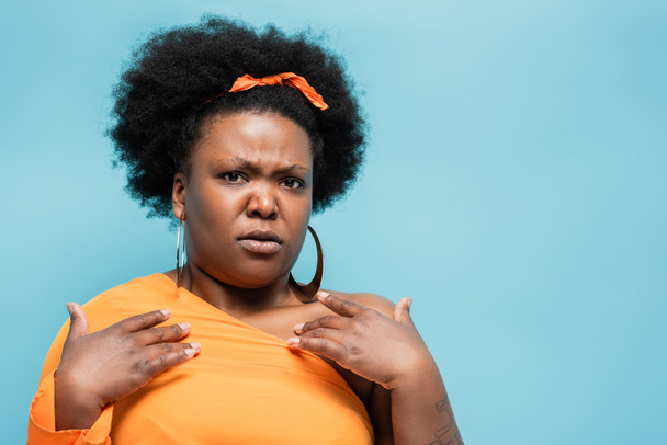 offended african american body positive woman in hoop earrings pointing at herself isolated on blue - Fotografie, Obrázek