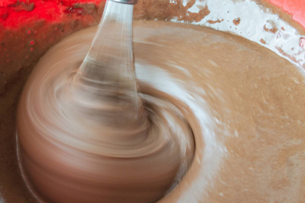 beat with a mixer with brown cake cream. pastry liquid smeared on kitchen utensils. there are air bubbles on the surface of the cream. - Photo, image