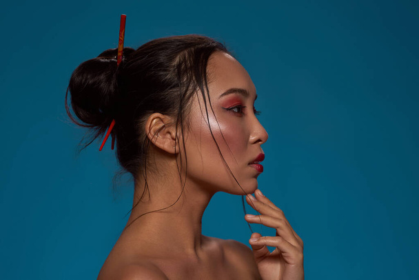 Partial side view of thoughtful stylish asian girl looking away. Profile of attractive young brunette slim woman. Female beauty. Isolated on blue background. Studio shoot. Copy space - Foto, Imagem