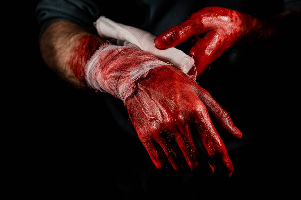 A man covered in blood bandages his hands - 写真・画像