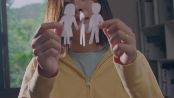 Hands of woman holding cutout paper family in living room. - Imágenes, Vídeo