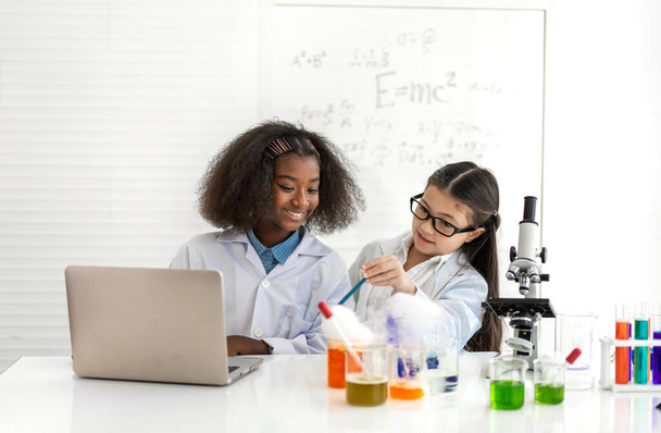 Skupina teenagerů se učí vědu a studuje chemický experiment a drží zkumavku v ruce v experimentální laboratorní třídě na stole ve školě.Vzdělání - Fotografie, Obrázek